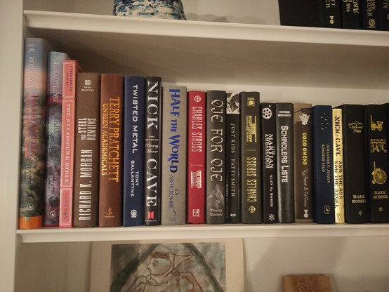 Photo of a shelf of books including two by Charles Stross