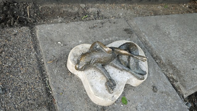 In that red circled area is a very small statue and this photo is a detailed picture. On a white marble lies a bronze statue of a dead squirrel, holding a pistol in one hand.