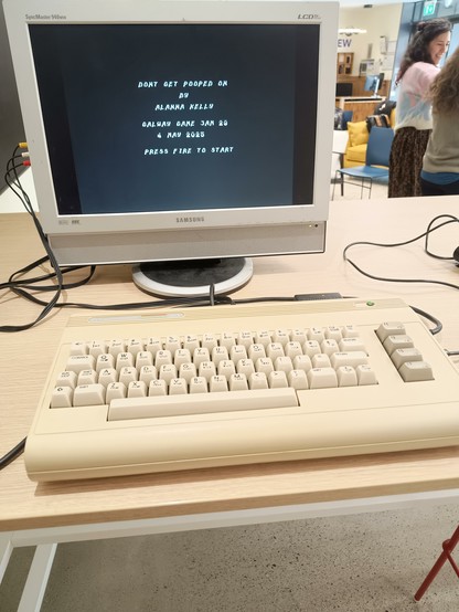 A Commodore 64G connected to a Samsung LCD monitor. A basic title screen for a SEUCK Game is on the display.