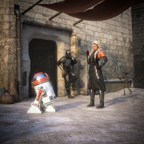 description by ChatGPT: In a dusty, sunlit alley of a stone-built spaceport, several characters from the Star Wars universe are gathered near an arched metal doorway set into a stone wall. A female Togruta—Ahsoka Tano—stands at the center of the scene with one hand on her hip and the other gesturing mid-conversation. She wears her signature dark grey and black robes, high boots, and her white-and-blue striped montrals and lekku drape over her shoulders.

To her left, a droid resembling R5-D4 tilts slightly forward as if listening or responding. The droid has a red, white, and blue cylindrical body and a domed head, with grime and scuffs indicating years of use.

Leaning casually in the doorway behind Ahsoka is the Mandalorian Din Djarin clad in full beskar armor, arms crossed and helmeted face angled toward the scene. He appears relaxed, observing the exchange. In the background to the right, a tall, spindly pit droid, walks across the sunlit ground.

Above the group, a fabric awning stretches out, casting a shaded area on the cracked, pale surface below. The setting evokes a remote outpost or desert settlement, peaceful yet brimming with story and silent anticipation.