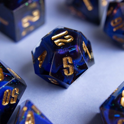 Ein D12 mit goldenen zahlen. Dahinter glitzert es und man sieht einen Farbwirbel aus Ultramarin, Schwarz und colorshifting mica.