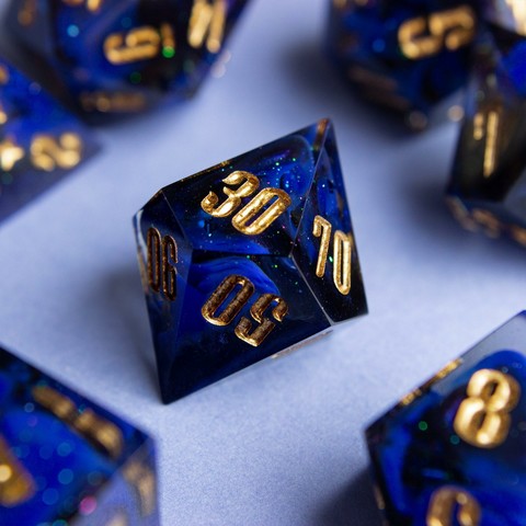 Ein D100 mit goldenen zahlen. Dahinter glitzert es und man sieht einen Farbwirbel aus Ultramarin, Schwarz und colorshifting mica.