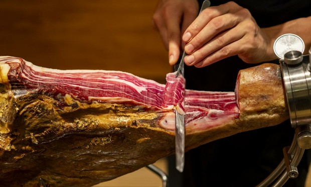 Una persona, cortando un jamón. (GETTY)