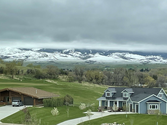 A layer of clouds concealing the tops of the local mountain range south-west of town in Sheridan Wyoming. Several homes are visible in the foreground of the photographs.