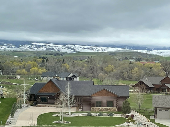 A layer of clouds concealing the tops of the local mountain range south-west of town in Sheridan Wyoming. Several homes are visible in the foreground of the photographs.