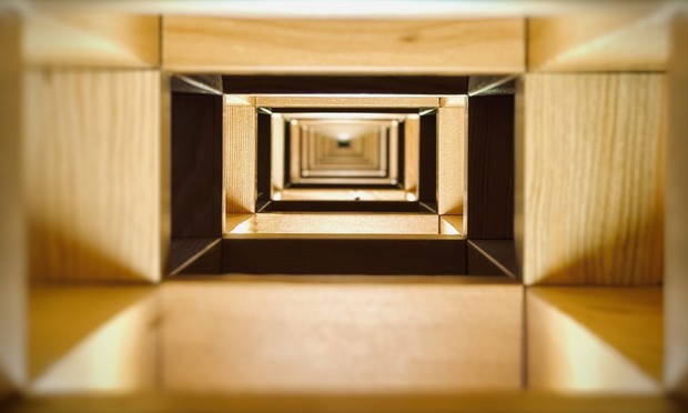 A perspective view through wall framework reveals a seemingly endless tunnel of two-by-four and four-by-four rectangular wooden supports, each unique section lit from underneath by individual incandescent bulbs.