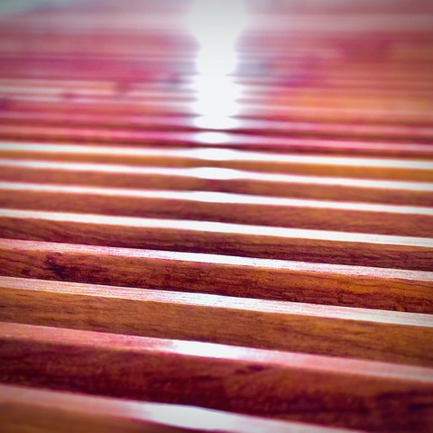 A point of white light reflects off repeating rows of slightly pink wooden two-by-four supports.