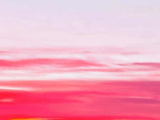 Red and pink clouds streak across the bottom half of a white sky as if paintbrush strokes on a canvas.