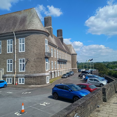 A picture of Carmarthen Castle. Looking. towards the car park. There appears to be a faded EU flag flying on the flagpole.