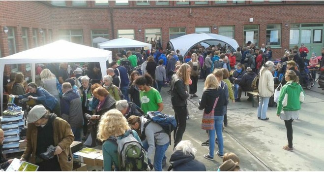 Ein Hof auf dem ein Flohmarkt stattfindet, im Hintergrund einige weiße Pavillons mit viele Menschen.