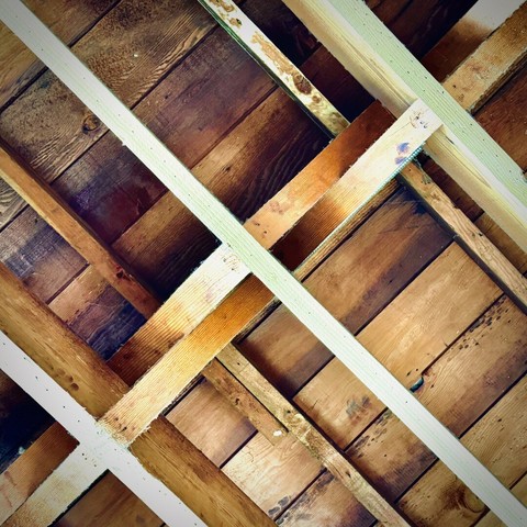 A wooden ceiling's framework/bracing forms multiple diagonal, symmetrical "X" patterns above.