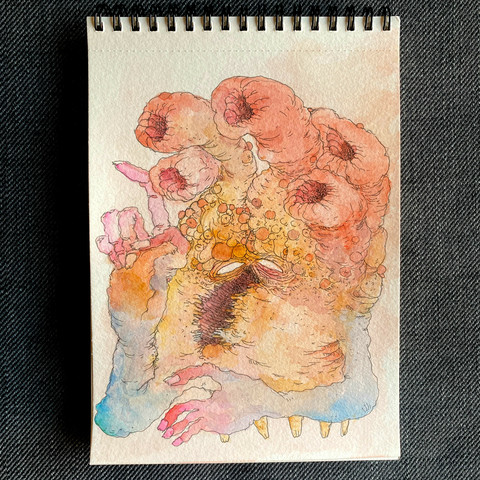Dibujo en acuarela de una criatura con brazos humanos y una boca vertical con ojos blancos y una cabeza que parece como un coral en colores naranjas amarillos y los brazos lilas, naranjas y azules. El dibujo aparece sobre un cuaderno rectangular de espiral con un fondo de una tela gris