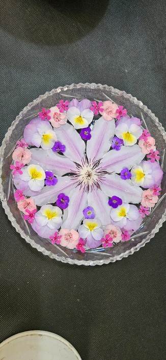 Floral display comprising clematis Nelly Moser, pinks, aubtetia, violas and phlox flowers.
