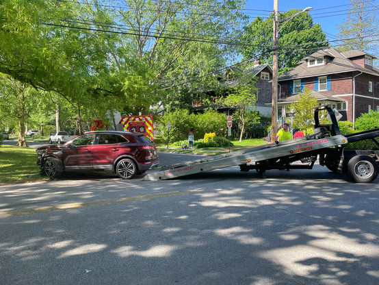 Red SUV with front end damage being loaded onto a flatbed truck.