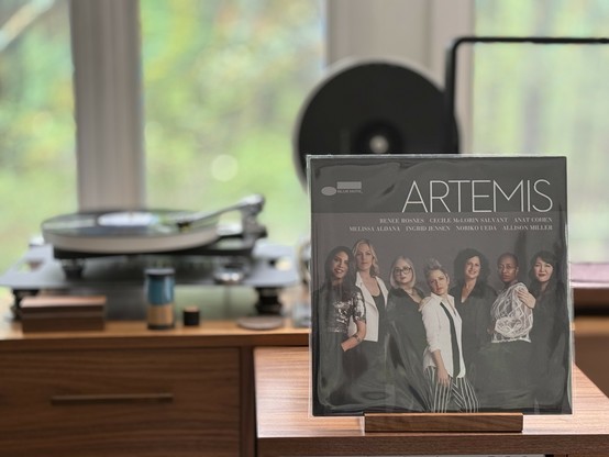 Artemis - Artemis LP cover.

Black band at the top with the Blue Note logo and the group name/title. A group shot below on a lighter grey background.

L-R Aldana, Jensen, Rosnes, Miller, Cohen, Salvant, Ueda.

The black LP plays on a Rega NAIA turntable to the left.