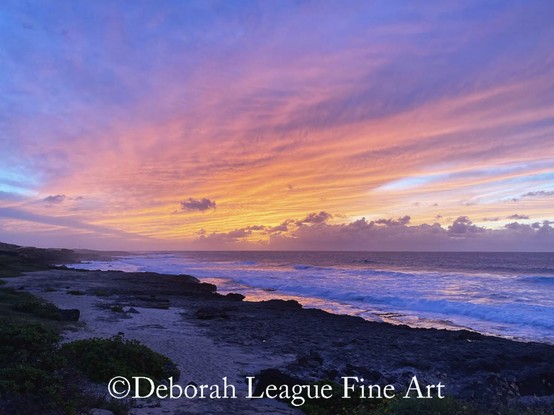 Enjoy the breathtaking beauty of a Hawaiian sunset in this coastal landscape photograph. The image captures a dramatic evening sky painted in vivid shades of orange, pink, purple, and blue as the sun dips below the horizon. Waves crash gently against the rocky shoreline while soft clouds float across the horizon, creating a serene yet powerful tropical scene. Perfect for nature lovers, travel enthusiasts, and anyone enchanted by the magic of island sunsets.

A breathtaking sunset illuminates the sky with vibrant hues of pink, orange, and purple over a rugged coastline. Waves gently crash onto the rocky shore, creating a serene and picturesque scene.