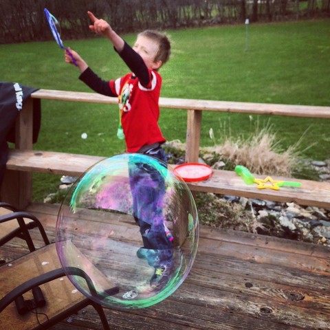 Eleven years ago we played with big bubbles and I tried to see what kind of photographs I could get of them. Here a bubble is coming towards camera while son points up to another that’s got some lift.
