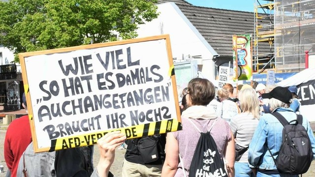 Foto von der Kundgebung in Rotenburg. Zu sehen sind rechts mehrere Leute von hinten. Links wird ein Schild in die Kamera gehalten auf dem steht: "Wie viel 'So hat es damals auch angefangen' braucht ihr noch?"