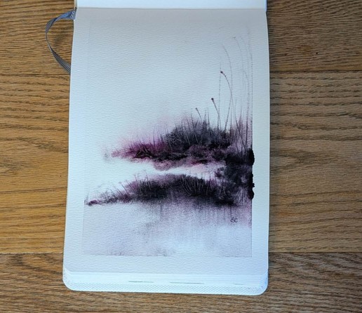 This is a atmospheric watercolor painting in portrait format in an A5 etchrlab sketchbook, using Daniel Smith Lunar Violet and Rose of Ultramarine. A little more than halfway down on the page starting on the right side is an upper landmass contented by a dark swatch tho a second lower thinner and slightly longer landmass.  More Rose of Ultramarine is visible in the to region (that doesn't reach the left side, the bottom one does).  From the bottom landmass dark vertical streaks reach down and granulate at the bottom of the page in more light values. Into the sky the color is very faint only really noticeable due to the white border. Grasses give texture and movement.