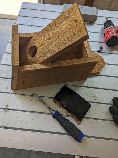 bluebird box with the front panel hinged open; tools sitting around in on the folding camp table
