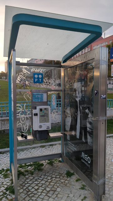 A phone booth. The phone is off the hook. There's an ad for a telecom company with a photo of Depeche Mode saying:
Waiting Ring
Enjoy the Silence