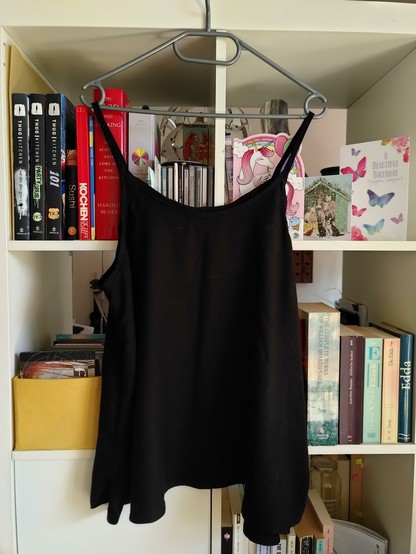 A drapy black spaghetti strap top, hung on my bookshelf.