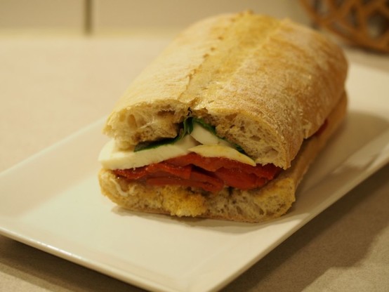 Das halbierte Sandwich mit Pilzpesto, gerösteter Paprika, Mozzarella und frischem Basilikum