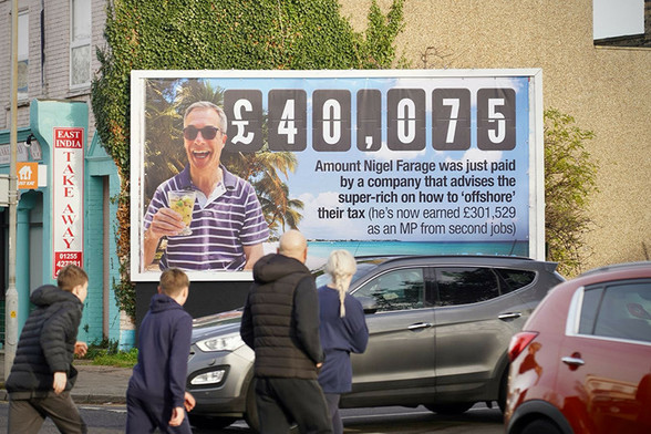Led by Donkeys poster. Farridge laughing on a tropical beach with a drink in his hand. 

Text: £40,075. Amount Nigel Farage was paid by  a company that advises the super rich on how to "offshore" their tax.

(he's now earned £301,529 as an MP from second jobs)