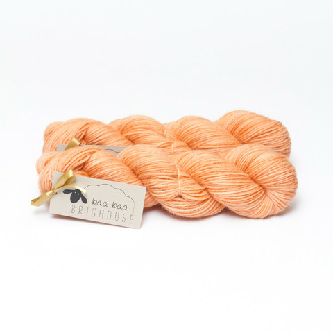 Picture shows two skeins of yarn, one in front of the other, in shades of orange.