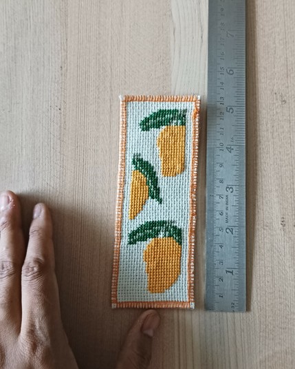 The bookmark next to a scale and my hand on a wooden board