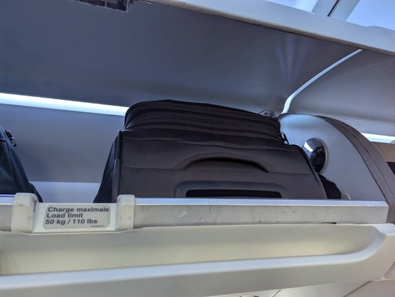 A photo of a carry-on bag in an  overhead compartment of an Airbus A330-200.
The bag is utilizing more "frontage" of the compartment than necessary because the traveler didn't bother turning the bag sideways.