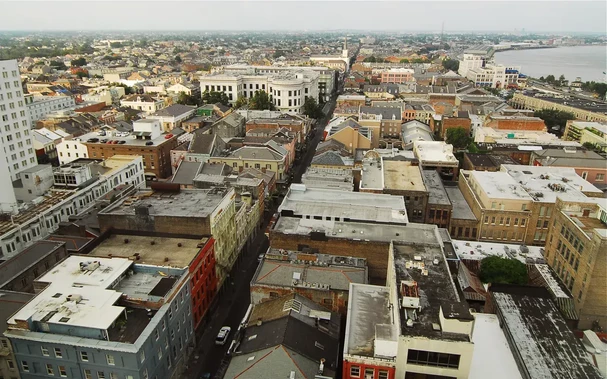 The image shows a panoramic view of an urban landscape, likely from a high vantage point. It features a densely packed arrangement of buildings with various architectural styles, including residential and commercial structures. The rooftops are a mix of different colors and materials, and the streets appear narrow. In the distance, there seems to be a river or large body of water, and the skyline includes more modern buildings. The overall scene gives off a vibrant city atmosphere.

Image Credits: Wikimedia / Chris Litherland / CC BY-SA 3.0