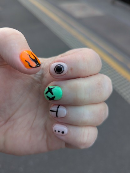 Manicure featuring nails with bright and neutral base colours, and bold simple designs drawn in black.