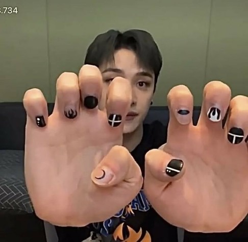Bang Chan showing his nail art done in black and white with simple shapes.