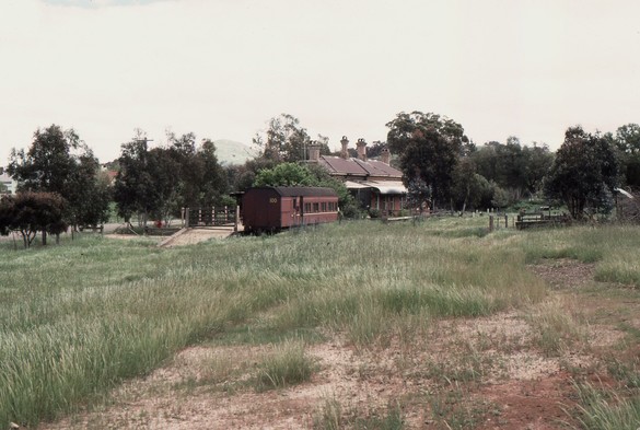 A disused railway station building and platform stands in the middle distance with a historic carriage standing at the platform.  All the tracks have long been removed, but the site of the former railway station yard is kind of discernible at right.  The passenger platform has a sloping end leading down to ground level - a style that is no longer to be seen on active station platforms, this surviving in 19th century configuration presumably because this platform has long been disused.