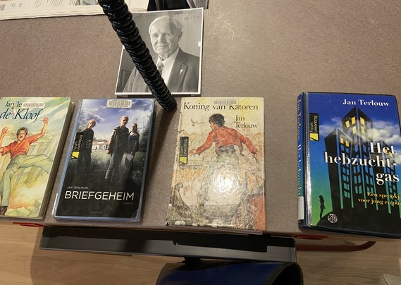 Vier kinderboeken op een rij met daarboven een geprinte foto van Jan Terlouw. Alles liggend op een tafel.