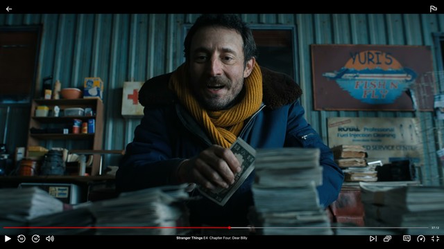Screenshot of the show showing a still of a man counting money with the play controls enabled showing the episode title and time bar. In the shot, there’s a sign on the wall in the background, slightly out of focus reading "Yuri’s Fish n' Fly"