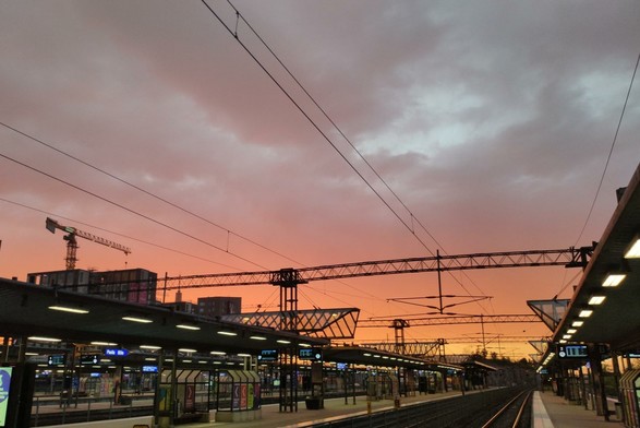 Photo of railway station platforms in the evening with lights on, several tracks and light strips meeting at the vanishing point, creating a pleasing arrangement. The sky is flaming orange. Just before 10 pm, Finland.

Photo by me