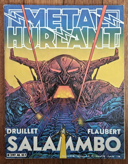 A cover of the Métal Hurlant magazine. The colorful art features a little spacecraft aiming at the wide-open mouth of a monstrous figure. Title reads SALAMMBO.
