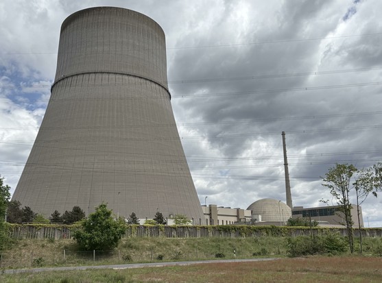 Das ehemalige Kernkraftwerk Ems in Lingen an der Ems. Im Vordergrund ist der riesige Kühlturm zu sehen, rechts unten im Bild das halbkugelförmige Reaktorgebäude. Im Hintergrund sieht man mit Quellwolken gedeckten Himmel; insgesamt wirkt die Szenerie bedrohlich.