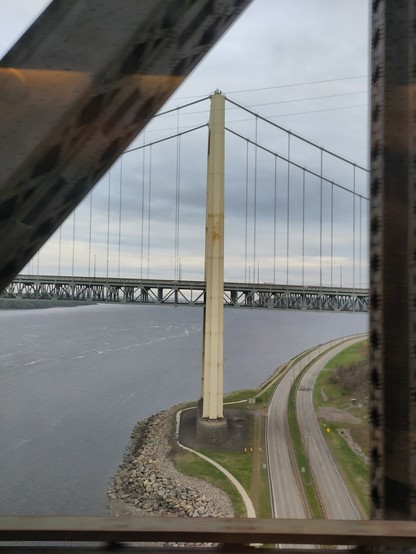 Foto. Eine Hängebrücke, im Vordergrund Stahlfachwerkträger einer weiteren Brücke.