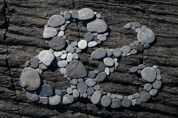 An ampersand formed of slate stones, laid on a rock.