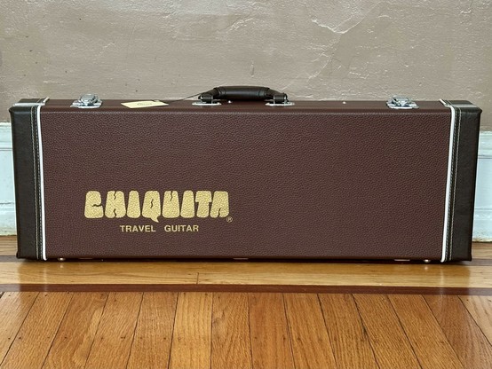 Side of the closed case covered in brown Tolex with “CHIQUITA TRAVEL GUITAR” silkscreened in gold.