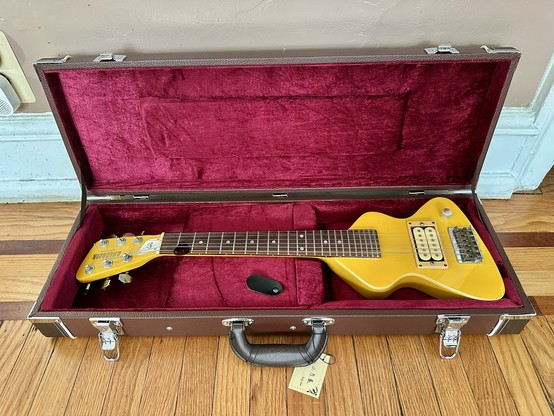 Case opened with the guitar inside. The interior is lined in red velvet.
