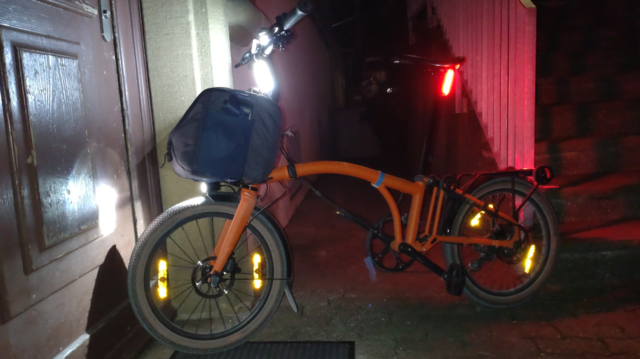 Mein orangenes Brompton Electric G-Line in voller Beleuchtung im Profil.
