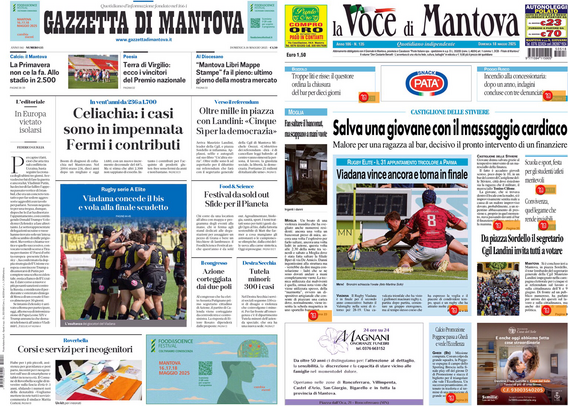 Un tablet su un tavolo di legno mostra le prime pagine di due giornali. A sinistra, la "Gazzetta di Mantova" con vari articoli, tra cui uno sulla celiachia e un altro su una partita di rugby. A destra, "La Voce di Mantova" con un titolo principale che parla di una giovane salvata con un massaggio cardiaco e un articolo sul rugby. Entrambi i giornali presentano immagini e testi vari.  .