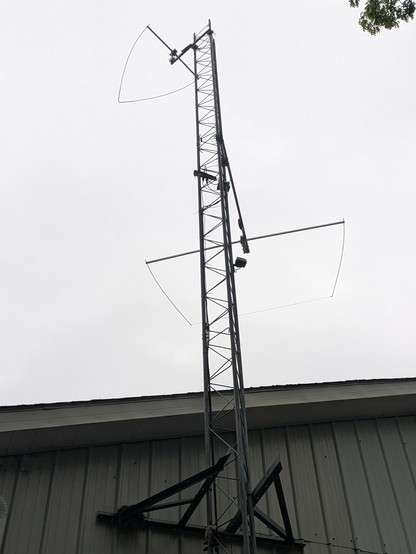 Picture of a tower with two antennas mounted to it, a square 10 meter omni antenna around the middle and a triangle 6 meter antenna near the top.
