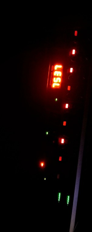 The photograph composed in total darkness shows a dark background with a digital display and several illuminated buttons. The display is lit in Amber and shows the letters "Lesl." Below the display, there are several buttons, some of which are lit in red, and a few in green. The red-lit buttons are arranged vertically, with one directly below the display and others spaced out. The green-lit buttons are located at the bottom of the image, with two sets of four lights each. The overall scene is set against a black background, emphasizing the red and green lights.

 Ovis2-8B

🌱 Energy used: 0.154 Wh