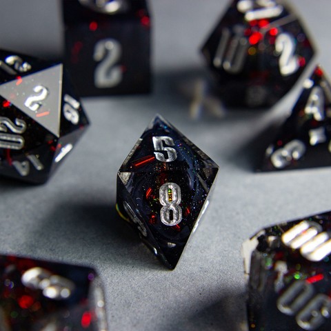 Zu sehen ist ein D8 mit schwarzen swirls. Die Swirls sind von roten Metallflakes und Glitter umgeben.

Die Nummern sind silber geinked.