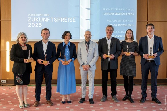 Gruppe von sechs Personen hält Auszeichnungen während der Verleihung des Zukunftspreises 2025 in einem Saal. Hintergrund zeigt Präsentation mit verschiedenen Preisnamen. Boden ist mit rotem Teppich bedeckt.
Preisträger*innen der Zukunftspreise der Universität zu Köln. V.l.n.r: Prof.‘ Dr.‘ Aleksandra Trifunovic, Jun.-Prof.‘ Dr.‘ Ann-Marie Waldvogel, PD Dr. Ansgar Hudde, Rektor Joybrato Mukherjee, Prof. Dr. Thomas Widlok, Jun.-Prof.‘ Dr.‘ Sofie Møller, Prof. Dr. Christopher Roth